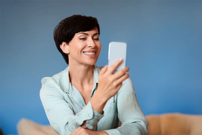 a female watching her phone and smiling